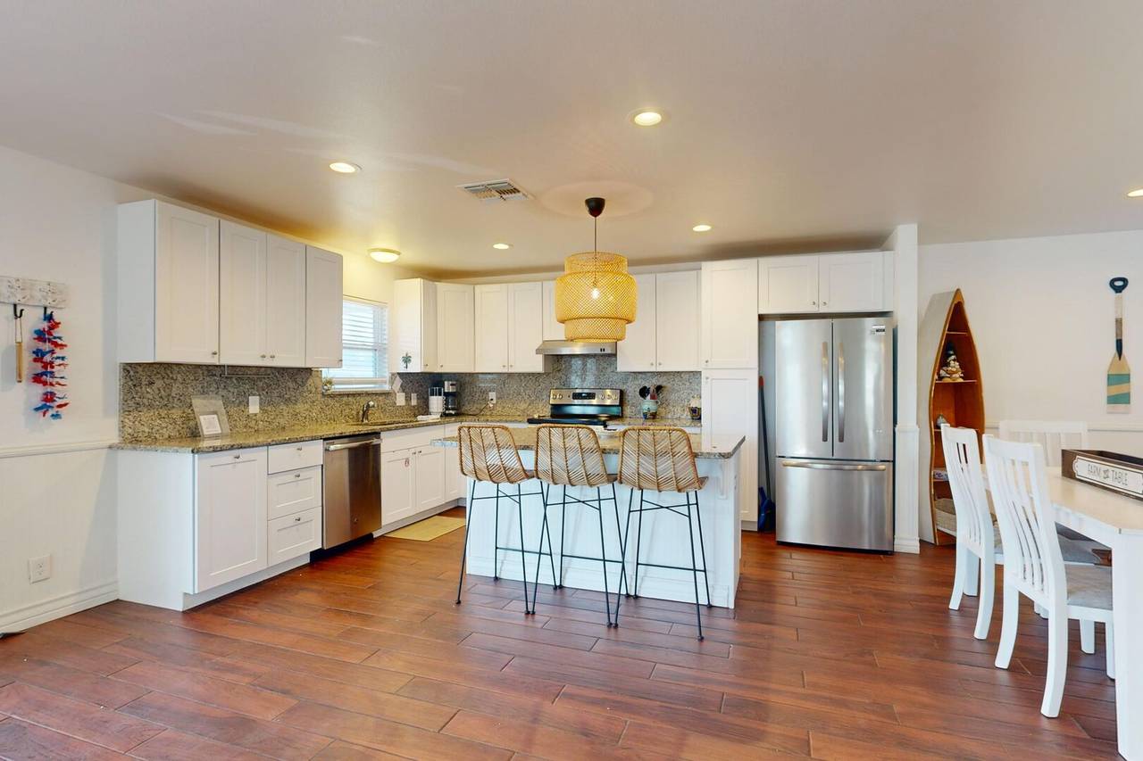 Full kitchen with granite counters and island seating at The Farley Beach House
